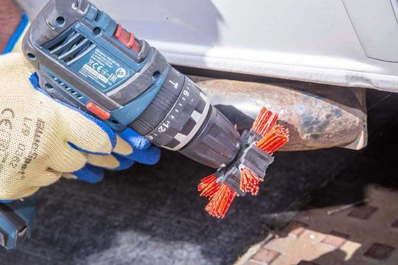 Abrasive Nylon Brush with red abrasive bristles and black plastic hub mounted on a cordless drill