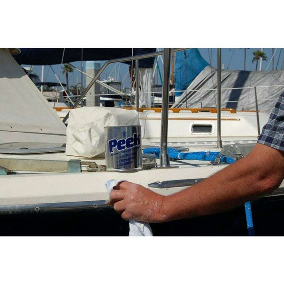 Peek Metal Polish in a blue and white tube beside a boat, shown being applied with a cloth to a metal surface