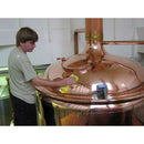 Peek Metal Polish tin beside a worker polishing a large copper metal vessel