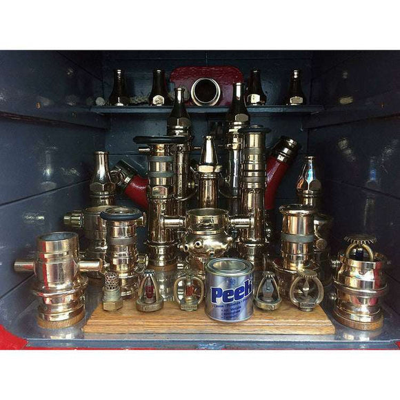 Peek Metal Polish tin displayed among polished silver metal fittings and valves