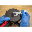 Sealey 115mm angle grinder with black disc, red handle and silver spindle wrench being adjusted